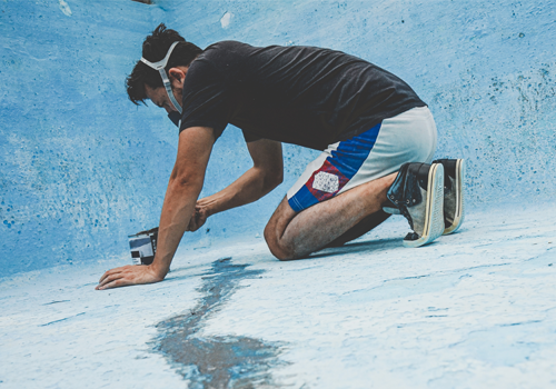 male pool repair person fixing the pool floor lining